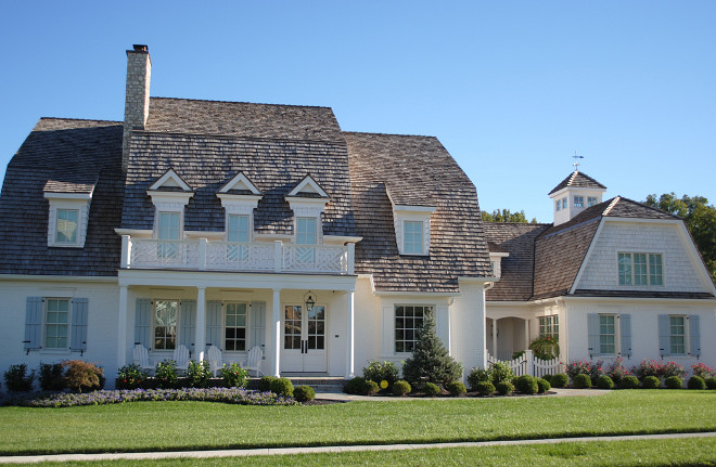 Gambrel Home exterior Reno. Gambrel exterior reno. This grambrel roof estate features cedar shakes, with shake siding and painted brick. The balcony has a Chippendale railing. Other features include stone chimney and porch as well as a custom built cupola. Shutter color is Porter Paint, Steel City. #Gambrel #Gambrelhome #GambrelhomeReno #GambrelhomeExteriorReno Stacye Love Construction & Design, LLC