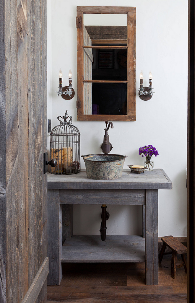 Farmhouse Bathroom. Authentic Farmhouse bathroom with custom vanity made from reclaimed Wyoming snow fence wood is a home for an antique milk bucket fashioned into a sink. The mirror is made from an old window frame, and the light fixtures from old plumbing fittings. Authentic farmhouse interiors. #Farmhousebathroom #bathroom #farmhouse #Farmhouseinteriors #AuthenticFarmhouseInteriors Dragonfly Designs