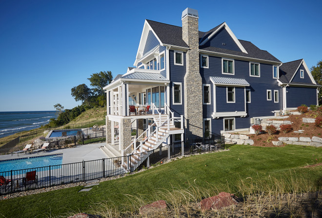 This navy home exterior, painted in Benjamin Moore Hale Navy, features a nautical first impression with shingle-style details, metal roof accents and handsome stone columns. Trim paint color is Benjamin Moore OC-17 White Dove. Exterior Trim: Trim, Soffits, Facia, Lintesls all Smart Trim in White Dove OC-17 by Benjamin Moore. Mike Schaap Builders