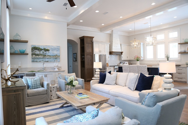 Family Room. Coastal Open layout family with slipcovered furniture. To keep everything looking great but also functional, all of the furniture is slip covered in washable fabrics. It all looks fabulous but is also practical for the owners. The pillows add great color and pattern by complementing the blue color palette. The fabulous painting you see above the bar is by the local artist Allison Wickey. #familyroom #openlayout #openinteriors #coastalinteriors #slipcoveredfurniture Old Seagrove Homes.