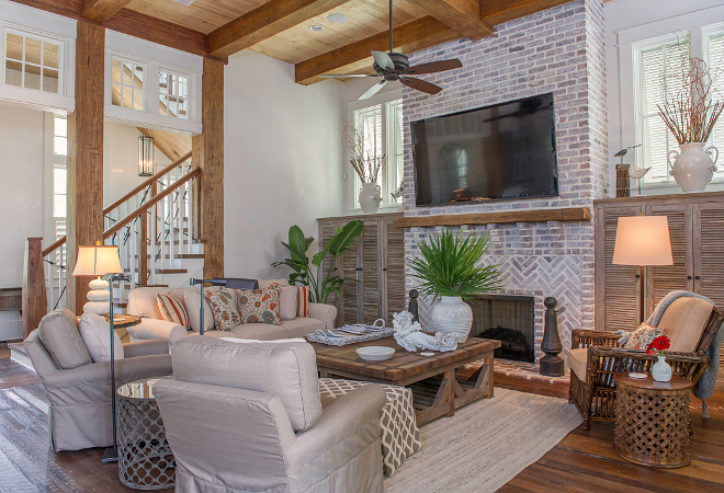 Rustic Living Room. Farmhouse Living Room. This gorgeous farmhouse living room features a fireplace with exposed reclaimed brick lightly white washed, reclaimed pine beams and Cypress built-in cabinets. #livingroom #rusticlivingroom #Farmhouse #FarmhouseLivingroom #exposedbrick #whitewashedbrick #reclaimedbeams #cypresscabinet Interiors by Courtney Dickey and T.S. Adams Studio.