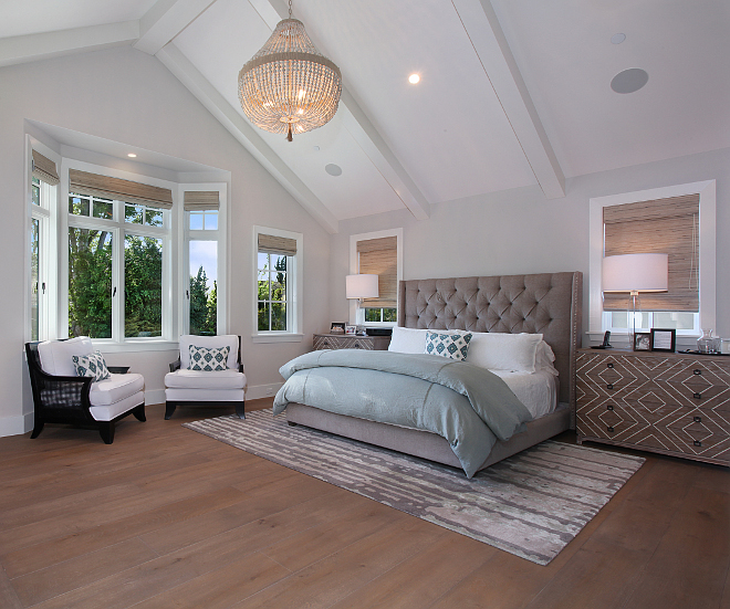 Master Bedroom. This relaxing master bedroom features custom upholstered bed with tufting and nail head trim, chevron nightstands and Jaipur rug, The vaulted ceiling features stained and paint grade beams. Patterson Custom Homes. Interiors by Trish Steele of Churchill Design. 