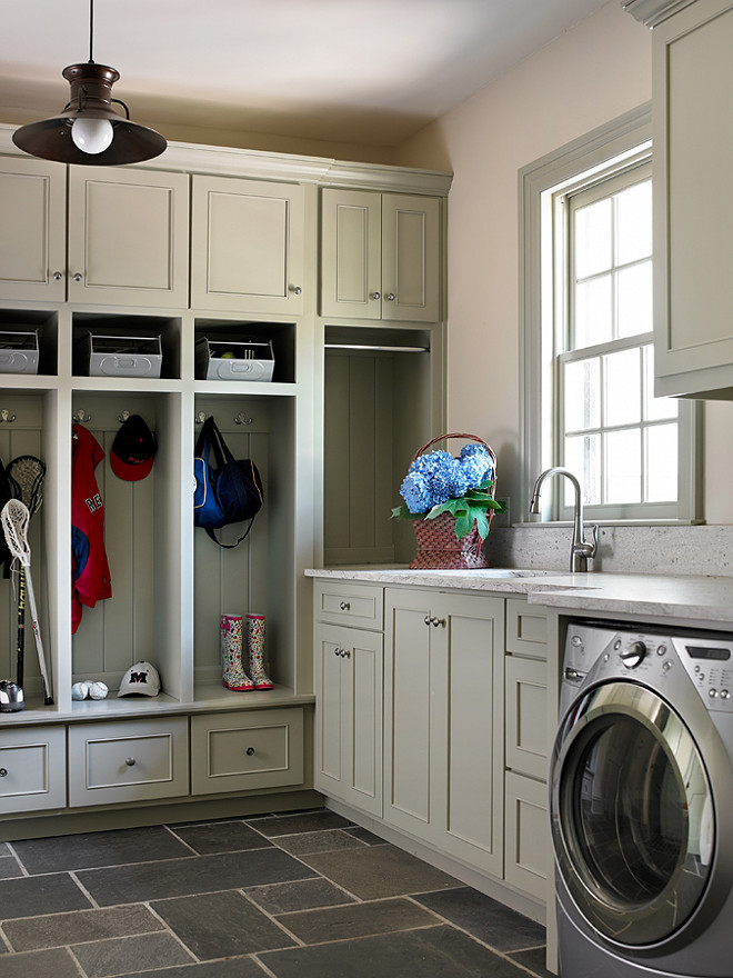 Mudroom and laundry room combined. Mudroom in laundry room featuring gray open locker cabinets filled with metal baskets over slate tiled floor. Laundry room with gray cabinets and white and gray countertops as well as silver front-load washer and dryer. #mudroom #laundryroom Tillman Long Interiors.