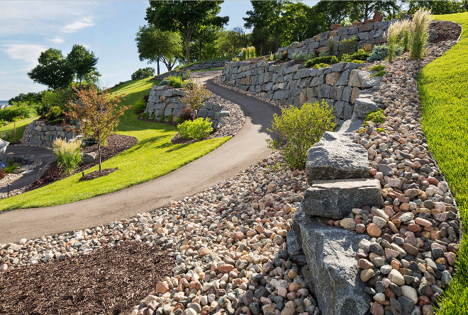 Sloped backyard. Sloped backyard landscaping ideas. Sloped backyard with mix of bluestone retaing walls, rocks, mulch and shrubs and trees. #Slopedbackyard Southview Design