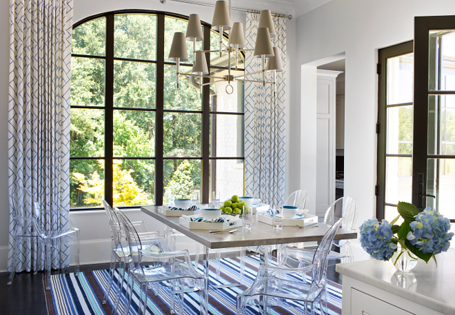 Breakfast room. Isn't this breakfast room fresh and fun? The polished chrome dining table with gray top is surrounded by Kartell Ghost Chairs over blue and purple rug layered over espresso wood floors. This space also features large steel cased arched window covered in floor-to-ceiling white and blue geometric curtains. #breakfastroom TS Adams Studio Architects. Traci Rhoads Interiors.