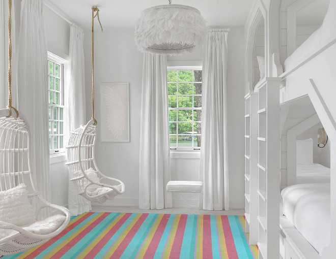 Bunk room with hanging chairs. All white bunk room with hanging chairs and colorful striped rug. #hangingchairs #bunkroom Amy Studebaker Design.