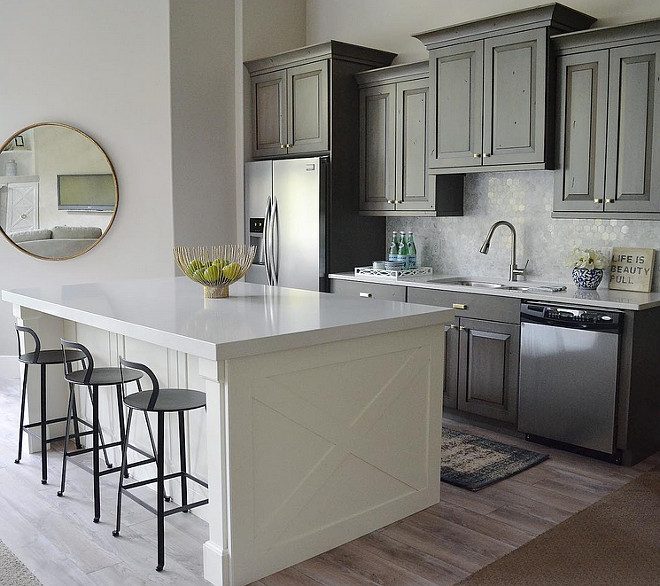 Gray kitchen with island. Wall paint color is Benjamin Moore Edgecomb Gray and the white island is Benjamin Moore Simply White. Gray cabinets are stained in a washed gray. Countertops are Pental Quartz in Lattice. Kitchen stools are Ballard Designs. Mirror is by Lighting Design. Sita Montgomery Interiors