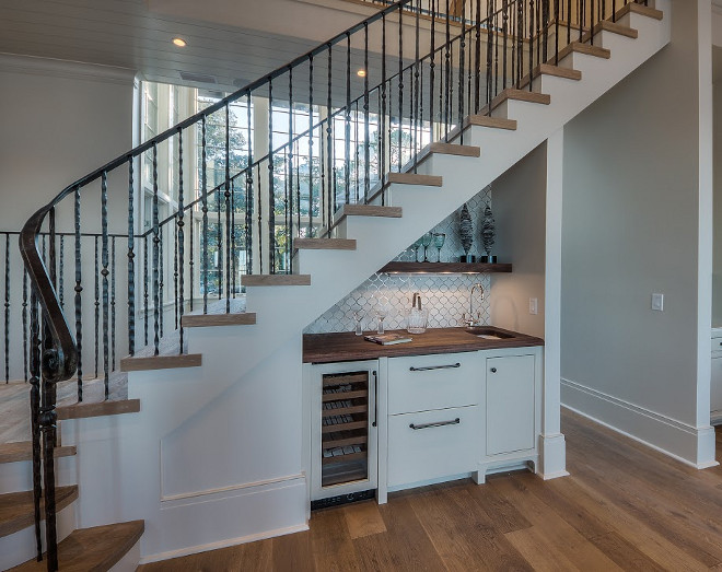 Kitchen wet bar tucked under staircase. Compact kitchen wet bar with butchers block countertop and open shelves tucked under staircase with wrought iron railing. #bar #wetbar #kitchenBar #undertstairsstorage #understaircase #barideas #wroughtironrailing #wroughtironstaircase