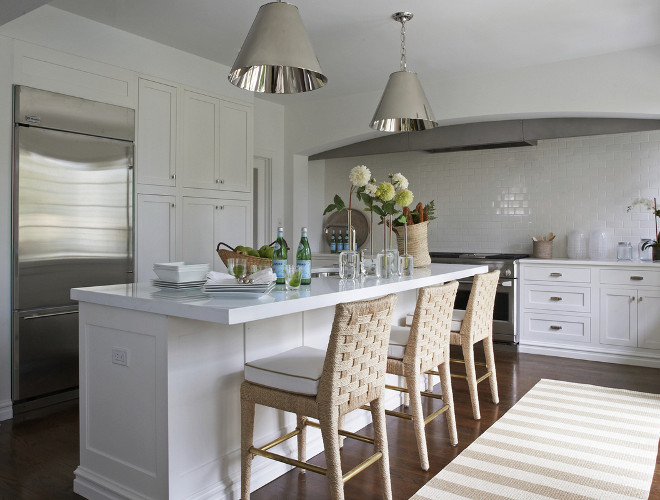 Kitchen. kitchen with Restoration Warehouse Altamont Metal Pendants in Polished Nickel over kitchen island. White center island houses stainless steel dishwasher and sink with modern kitchen faucet surrounded by woven barstools. White shaker kitchen cabinets with white quartz countertops and cooktop alcove with stainless steel range and white subway tile backsplash. Glass-front counter-depth refrigerator and chocolate stained matte hardwood floors. #kitchen Lynn Morgan Design