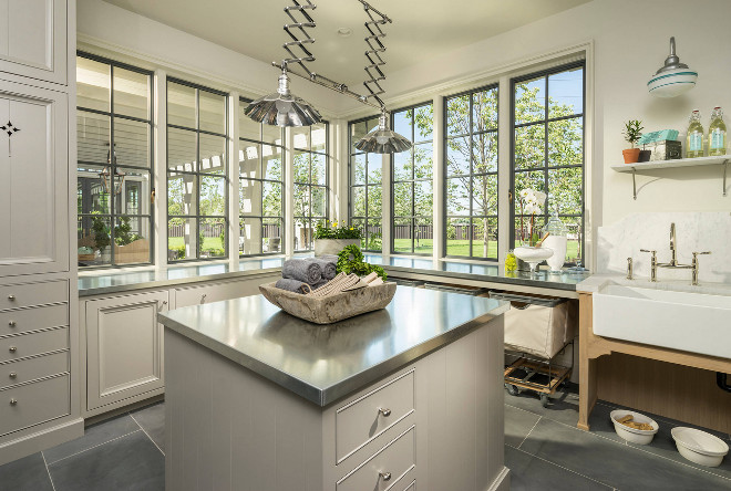 Laundry room. Laundry Room. Laundry Room with pale gray cabinets, pale gray island with stainless steel countertop. A washstand features a farmhouse sink with marble backsplash. #Laundryroom #Laundryrooms #Laundryroom 