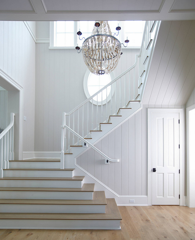 Foyer millwork. Light flooded foyer with white tongue and groove paneled walls, custom millwork and white oak hardwood floors. Chandelier is the Lowcountry Originals Large Empire with Oysters Shells Chandelier. #foyer #millwork #tongueandgroove #wallmillwork #whitemillwork #LowcountryOriginals #Large #EmpirewithOystersShells #Chandelier.