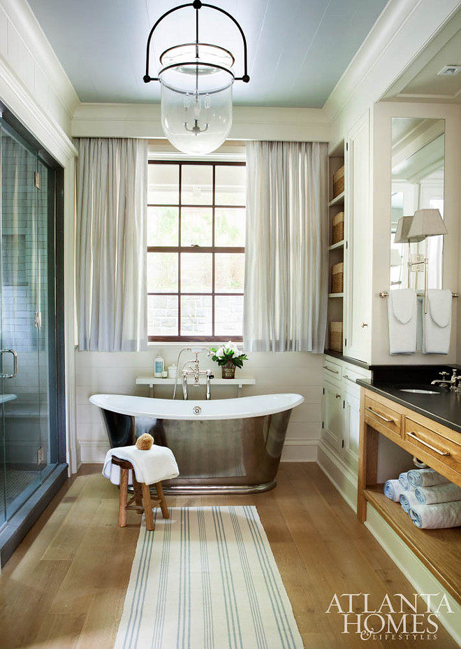 Bathroom. A Waterworks tub in the master bath creates a stunning focal point. Its classic charm is complemented by custom window treatments fabricated by Willard Pitt Curtain Makers. Lighting is from Urban Electric and the runner is Dash & Albert. Atlanta Homes and Lifestyle. T. Duffy & Associates 