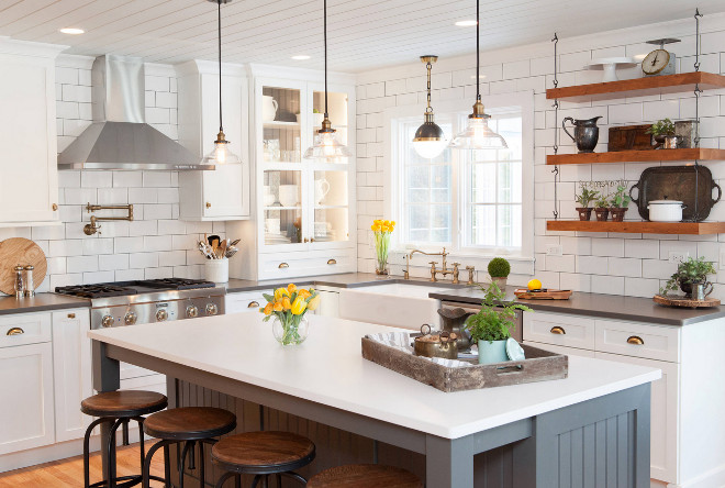 Farmhouse style kitchen. Modern Farmhouse style kitchen. Farmhouse style kitchen with retro lighting, reclaimed wood open shelves, grey island, white perimeter cabinets and brick style subway tiles. #farmhousestylekitchen #farmhousekitchen #farmhousestyle Advance Design Studio, Ltd.