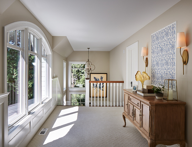 The upper hall features a framed wallpaper by Thibault above an antique sideboard. Upper Hall Sconces: Hudson Valley. Paint Color is Accessible Beige by Sherwin Williams. Accessible Beige. accessible-beige-by-sherwin-william Vivid Interior Design. Hendel Homes