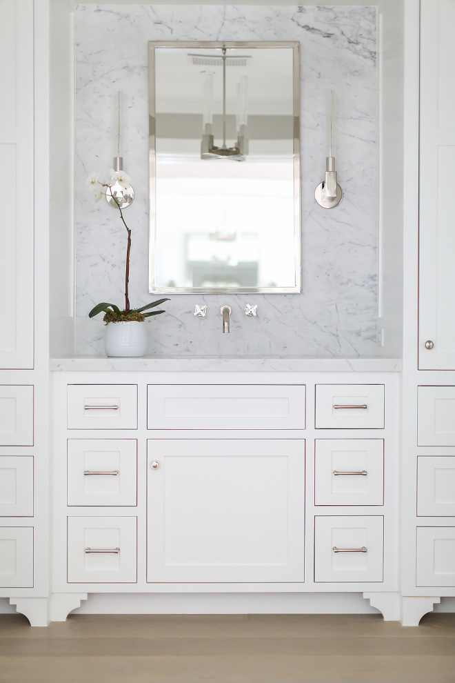 Bathroom marble slab backsplash. Counter and slab backsplash is Statuarietto marble with a honed finish. Wall mounted faucet is by Rohl. The bathroom mirror is Restoration Hardware in polished nickel. Sconces are from Restoration Hardware Modern. A brand new store from Restoration Hardware. #bathroom #marble #slabbacksplash #cabinet #countertop #mirror #sconces #restorationhardwaremodern Winkle Custom Homes. Melissa Morgan Design. Ryan Garvin Photography