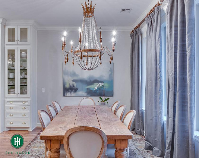 Dining room. The dining room is set in front of wall to wall windows. The natural light brings in beautiful light to the space and also creates balance between the dark window treatments and the soft palette of the dining set. The chandelier is from Cyan Design "Alexandra Chandelier". The curtains are Dupioni Silk Drapes from Pottery Barn in Platinum Gray. The table was previously owned by the client and the Louis style chairs are made by Zentique (can be purchased through Wayfair). The art resembles the outdoors and adds a pop of color to the space. #diningroom Ivy House Interiors