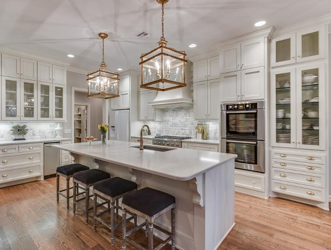 Kitchen. From a design perspective, this kitchen has an open layout, with the dining room and living space adjoining to create a large space for entertaining. The kitchen is the statement of the space, donned in Benjamin Moore Stonington Gray, the cabinetry reflects beautifully in Benjamin Moore, Linen White. The counter tops are Caesarstone, "London Gray" which for a kitchen is the best material to use, since it does not stain. The backsplash is Calacatta gold beveled edge subway tile. The hardware is in a satin brass finish, with a mixed collection of pulls and knobs from Atlas Hardware. The statement of the kitchen are the gold lanterns from Visual Comfort "Mykonos Lantern" in gilded iron, The Louis style stools are from a local antique store that was re-finished in a black velvet fabric. The appliances are Wolf brand stove and Bosch ovens. Overall, the look is elegant and sophisticated which reflects the clients' personalities. Ivy House Interiors