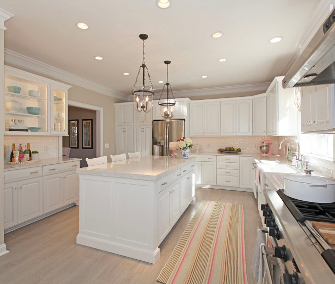 Kitchen Renovation. Not even a year ago, this room was filled with orange-gray floor tiles, builder-grade cherry cabinets and dark granite countertops with a green glass mosaic tile backsplash. The kitchen gets amazing sunlight, but with all the dark finishes it felt very dark and cavernous. I longed for a white, light, bright kitchen, and designed every detail of our budget-friendly update by painting rather than replacing all the cabinets, adding custom woodwork to give our builder-grade cabinets and island a higher-end look, tiling over the old flooring with a more modern, wood-look tile, replacing the backsplash, switching out the granite countertops for Quartz, adding new lighting, hardware, farmhouse sink and bridge faucet, and building open shelving over the wine bar. My favorite features include the large island with double-thickness countertop, the beveled subway tile backsplash and the farmhouse sink & bridge faucet combo. When friends visit, everyone comments on the crystal knobs on the cabinet doors. They make the kitchen feel so elegant and reflect the sunlight, creating prisms everywhere. The kitchen was a labor of love; renovating it took nearly 2 months, and it wasn’t fun to live through, but the result was completely worth it. The best compliment anyone can give me is that the kitchen renovation looks much more expensive than it really was! #kitchenrenovation #kitchenreno #kitchen #renovation #reno Home Bunch's Beautiful Homes of Instagram peonypartydesigns