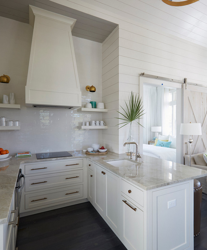  Small U Shaped Kitchen. This small U-shaped kitchen features a white French hood, stacked white floating shelves, suspended over an induction cooktop with pot and brass wall sconces. A kitchen peninsula is topped with Perla Venata quartzite fitted with a sink and modern faucet which overlooks the family room. Hardware is unlaquered brass. Small U Shaped Kitchen with quartzite countertop. #Smallkitchen #smallUShapedKitchen #quatzite #countertop small-white-kitchen-with-quartzite-countertop