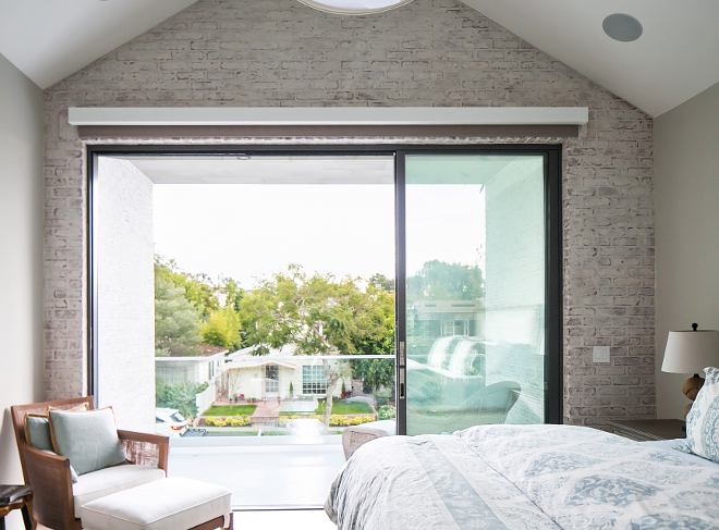 Bedroom. Bedroom with whitewashed brick. This master master suite features a vaulted ceiling, whitewashed brick accent wall, and sliding doors leading to a balcony off the bedroom. #Bedroom #Bedroomideas #whitewashedbrick Patterson Custom Homes