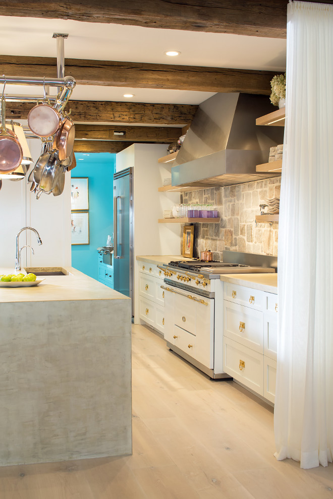 Eclectic Rustic Kitchen. Rustic kitchen with concrete waterfall island countertop, custom pot rack, open shelves, rustic reclaimed beams, open shelves and Fieldstone backsplash wall. Eclectic Rustic Kitchen #EclecticRusticKitchen #EclecticKitchen #RusticKitchen