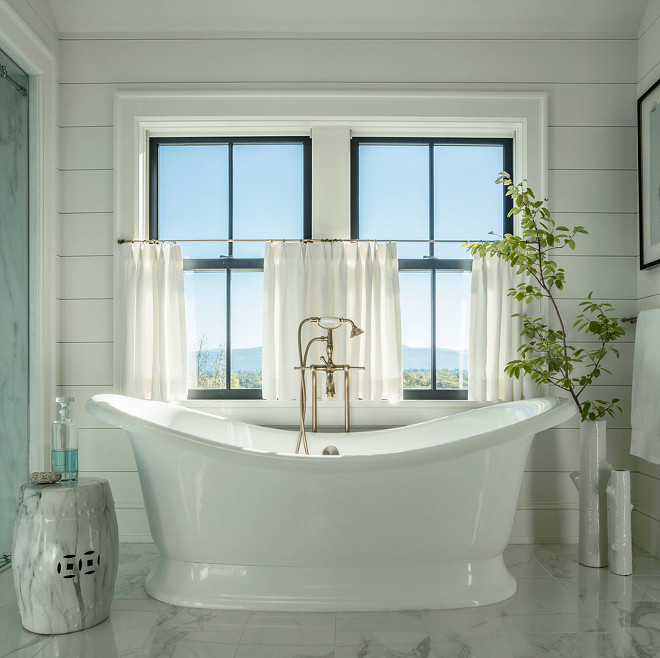 Farmhouse bathroom with black pane windows, cafe curtains and free standing bath. Wall paneling is tongue and groove. #Farmhousebathroom #blackpanewindows #cafecurtains #freestandingbath #paneling #tongueandgroove Roundtree Construction. TruexCullins Architecture + Interior Design