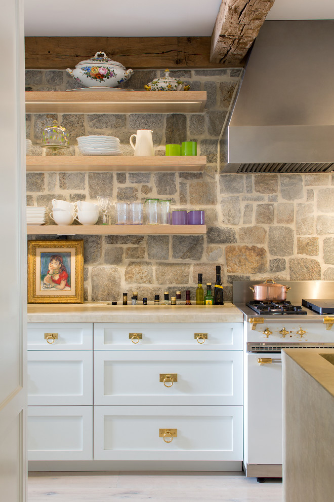 Kitchen Inspiration. Rustic Kitchen inspiration. Rustic kitchen with brass hardware, white cabinets, stone wall, wood countertop, reclaimed beams, reclaimed wood and floating shelves. Kitchen Inspiration. Rustic kitchen with brass hardware, beams, concrete countertops and built-in countertop oil storage - or ice bucket if you prefer. #KitchenInspiration #RusticKitchenInspiration #RusticKitchen