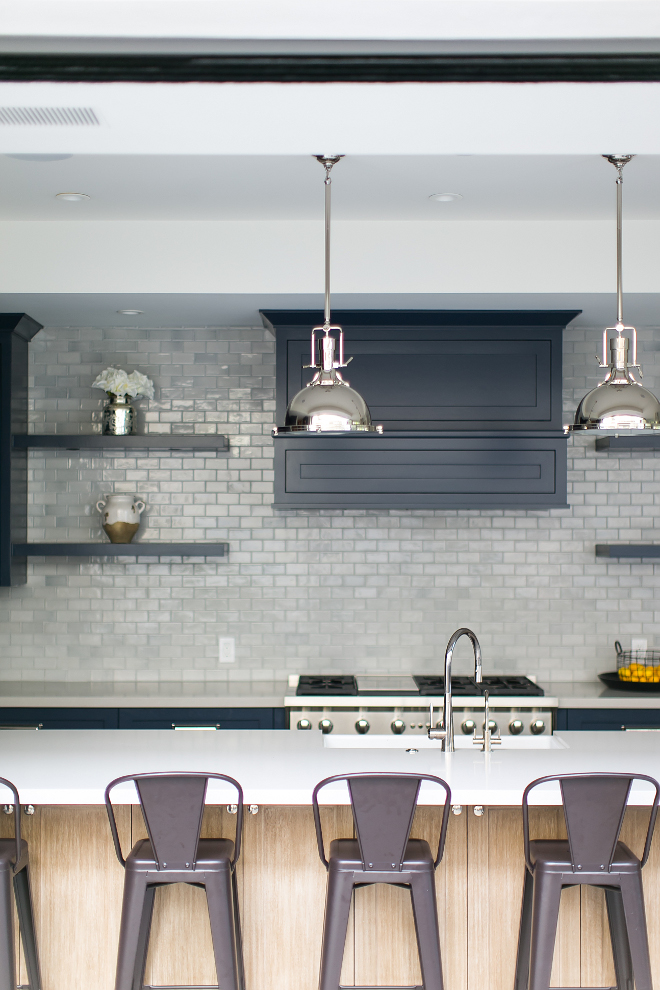 Kitchen Lighting. A counter-to-ceiling tiled backsplash, floating shelves, custom-made hood, and navy blue paint grade custom cabinets combine to create one unforgettable kitchen! Kitchen backsplash is 2"x4" Harbour Crackle Field Tile. Kitchen with navy cabinets, gray tile backsplash and industrial lighting. #kitchen #navykitchen #greysubwaytile #industriallighting Kitchen Lighting Ideas. Kitchen Lighting. #KitchenLighting Patterson Custom Homes