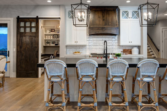 Modern Farmhouse Kitchen with white cabinets, stained wood hood and stained wood barn door. Modern Farmhouse kitchen. #ModernFarmhouseKitchen #ModernFarmhouse #FarmhouseKitchen #Farmhouse #Kitchen #whitecabinets #stainedwoodhood #stainedwood #barndoor Timberidge Custom Homes