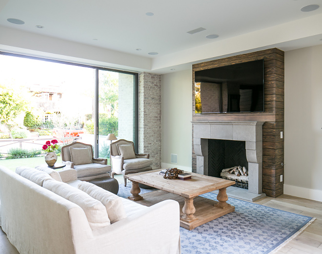 Neutral living room with stained shiplap fireplace. Neutral living room with stained shiplap fireplace. The exterior brick wraps around to the interior while the front sliding doors open, inviting the outdoors in. A shiplap accent wall behind the custom made fireplace draws the eye creating a unique focal point in the home's beautiful family room. #Neutrallivingroom #livingroom #stainedshiplap #shiplapfireplace Patterson Custom Homes