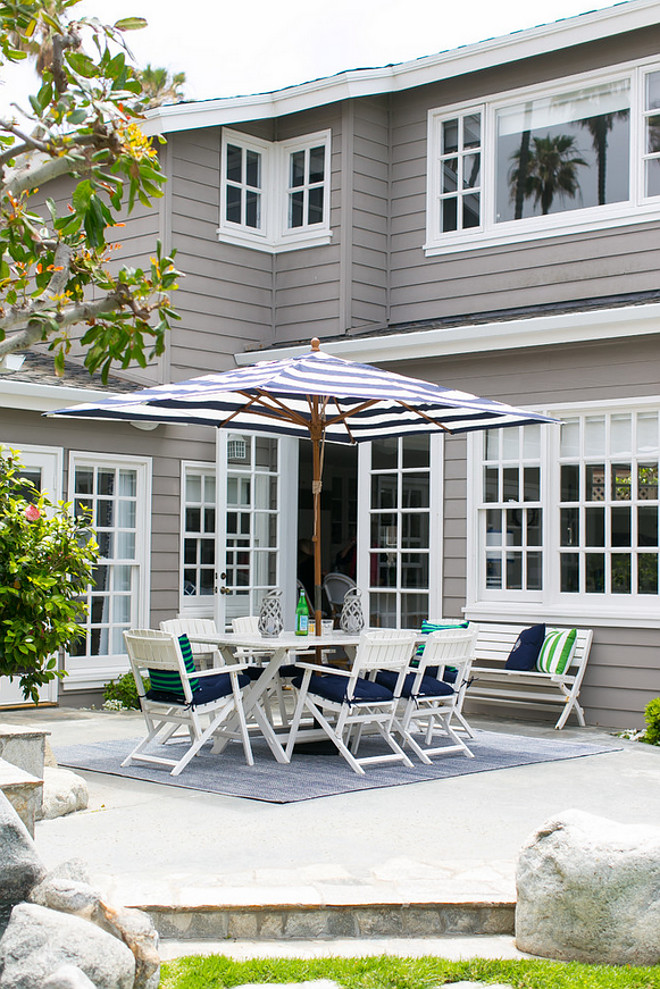 White outdoor furniture with blue cushions. This home features grey siding and white outdoor furniture with blue cushions. AGK Design Studio. Ryan Garvin Photography.