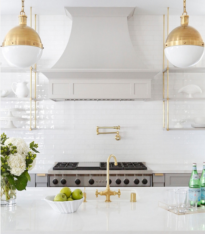 Brass Hicks Pendants. Kitchen feature Brass Hicks Pendants, brass faucet, brass pot filler and brass hardware. The countertops are polished Bianco Namibia. The white walls are a full height tile backsplash. The tile is Beveled white ceramic from Westide Tile. #Brass #HicksPendants #BrassHicksPendants #BiancoNamibia Boswell Construction