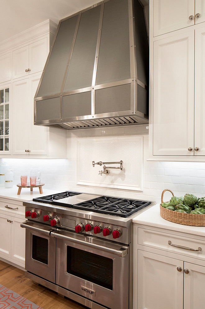 Kitchen Hood, A gray metal kitchen hood accented with steel straps is mounted to all white subway tiles framing a white tiled cooktop backsplash finished with a polished nickel pot filler above a Wolf range. Kitchen Metal Hood. White kitchen cabinet with Metal Hood. Metal Hood #itchenhood #MetalHood #kitchenMetalHood Kitchen Hood, Kitchen Metal Hood. White kitchen cabinet with Metal Hood. Metal Hood #itchenhood #MetalHood #kitchenMetalHood Martha O'Hara Interiors. John Kraemer & Sons