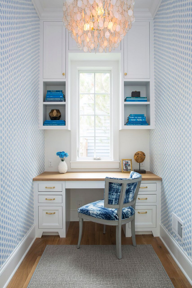 Kitchen Workstation. A blue tie dyed upholstered chair sits in front of a white built-in desk with gold pulls and wood desk countertop. The upper cabinets feature open shelves while the walls were covered in a blue block print wallpaper. Kitchen Workstation with blue and white wallpaper, built in desk, upper cabinets and capiz shell chandelier. Kitchen Workstation off kitchen. Kitchen Workstation. Kitchen Workstation #KitchenWorkstation Martha O'Hara Interiors. John Kraemer & Sons