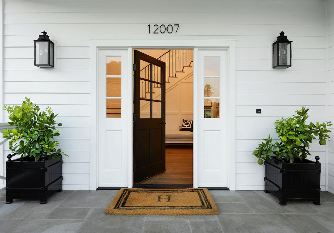 Black Front Door with black planters. Front porch with Bluestone floor tile, black front door with sidelights and black planters. #blackfrontdoor #blackdoor #planters #porch #frontporch #floortile #blueestone Hamilton Architects