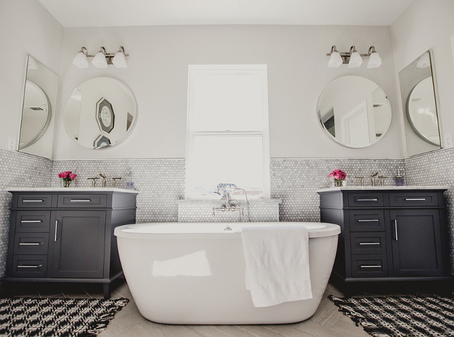 Farmhouse Master Bathroom, Farmhouse Master Bathroom with freestanding tub flanked by charcoal gray vanities from Home Depot, Penny Round Wall Tile and Light Wood-Like Herringbone Floor Tile #Farmhousebathroom #MasterBathroom #FarmhouseMasterBathroom #freestandingtub #charcoalgrayvanities #HomeDepot #PennyRoundTile #WallTile #LightWoodLikeTile #HerringboneFloorTile Beautiful Homes of Instagram @house.becomes.home