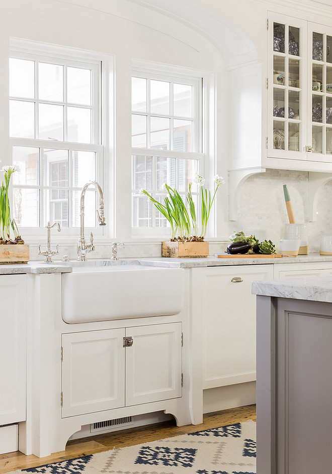 Farmhouse Sink Rohl Farmhouse Sink- The classic white farmhouse sink sits under casement windows that allow lots of natural light inside and provide garden views. The cabinet underneath holds paper towels and cleaning supplies. A lovely arched detail over the sink area mimics arches used in other parts of the home. It helps soften the room. A gray and navy area rug adds color, pattern and a textural element to the kitchen #Farmhousesink #casementwindows #kitchen #sink Nancy Serafini Interior Design