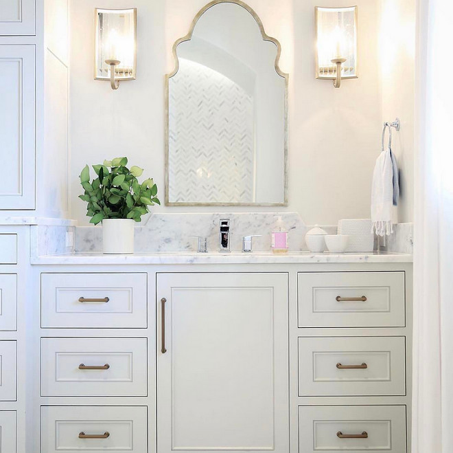 Bathroom Mirror and Sconces. In this bathroom, a Moroccan mirror add gorgeous curvilinear shape and shine in combination with the antiqued mirrored sconces. Mirrors: Wisteria. Sconces: Currey and Co. #Bathroom #Mirror #Sconces Old Seagrove Homes