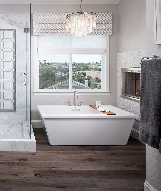 Bathroom Tub Lighting. The tub chandelier is Restoration Hardware – 1920’s Odeon. Tub is Pirch MTI Whirlpools. Window treatment is Maxwell and the fireplace tile is 1 x 2 Rock face white marble mosaic. Bathtub nook with freestanding, chandelier and fireplace. #Bathroom #Tub #Lighting #bathtubnook #lighting #tublighting Tracy Lynn Studio