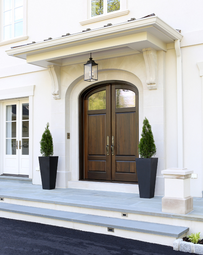 Front Door. The front door features a limestone surround with a wrought iron hanging lantern. The custom curved top paneled mahogany door has antique glass. Standing seam copper roof and bluestone terrace complete the entry. #FrontDoor Knight Architects LLC