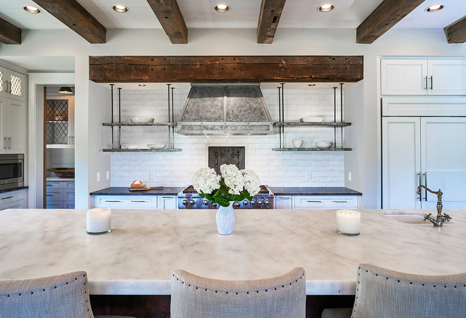 Kitchen. Kitchen Design. Reclaimed and warm wood tones will always be a player when it comes to farmhouse designs. This farmhouse kitchen, designed by Markalunas Architecture Group, features thick Carrara marble slab countertop, reclaimed beams, brick backsplash and metal shelves beside zinc hood. Kitchen with thick slab countertop, reclaimed beams, brick backsplash, Carrara marble and metal shelves beside zinc hood. #Kitchen #KitchenDesign #Kitchens #thickslab #thickcountertop #reclaimedbeams #brickbacksplash #Carraramarble #metalshelves #zinchood