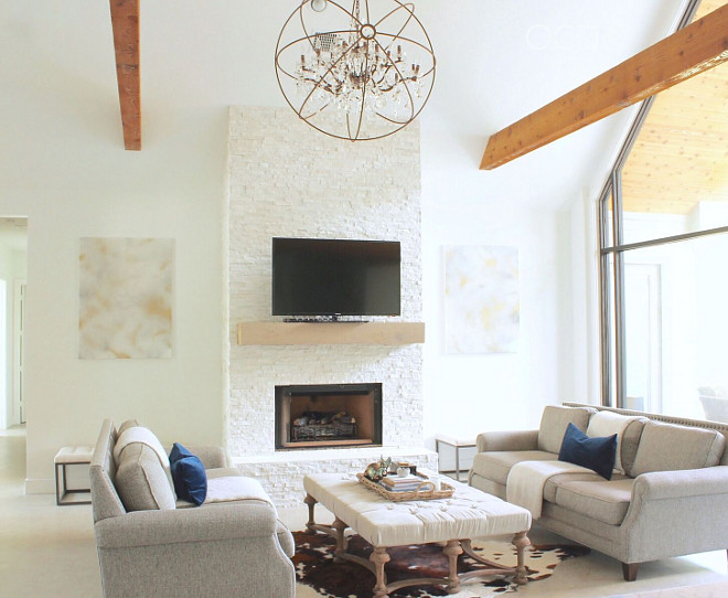 Sherwin Williams Extra White. The floor are sealed concrete. Our living room features a cathedral ceiling, cedar wrapped beams, and a floor-to-ceiling quartzite fireplace. Fireplace mantle is custom made from White Oak with a Classic Grey stain to give it a weathered look. The fireplace is clad in Glacier Splitface Quartzite. #SherwinWilliamsExtraWhite Beautiful Homes of Instagram @organizecleandecorate