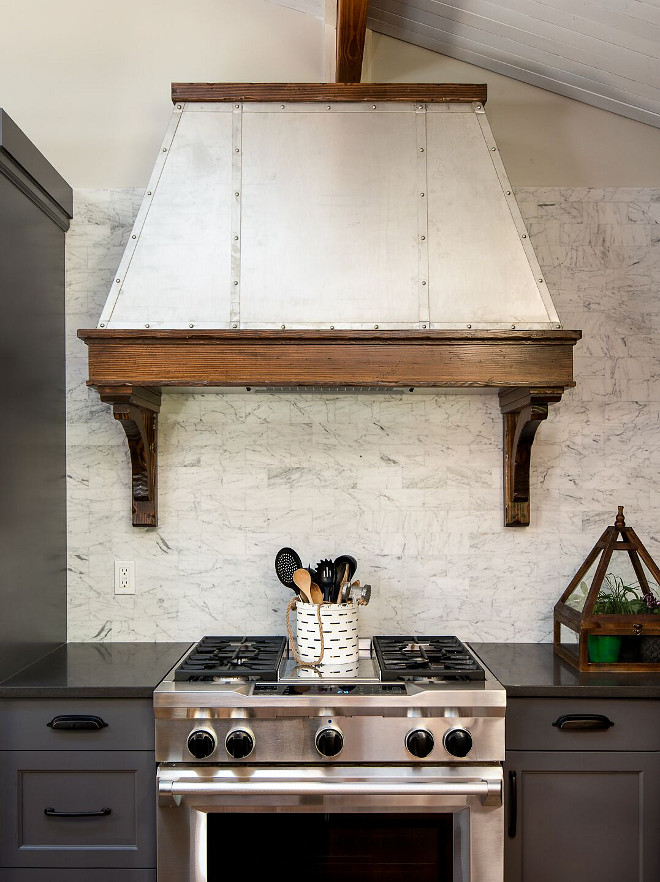 Zinc Hood. Farmhouse Zinc Hood. Stained wood trim and corbels add warmth to the metal kitchen hood. Farmhouse kitchen with zinc hood, grey cabinets, charcoal grey quartz countertop and Carrara marble backsplash tile. #Zinc Hood. Farmhouse Zinc Hood. Farmhouse kitchen with zinc hood with stained wood, grey cabinets, charcoal grey quartz countertop and Carrara marble backsplash tile #ZincHood #Farmhousehood #farmhouseZincHood #Farmhousekitchen#greycabinets #charcoalgreyquartz #greyquartzcountertop #quartzcountertop #Carraramarble #backsplash #tile reDesign home llc