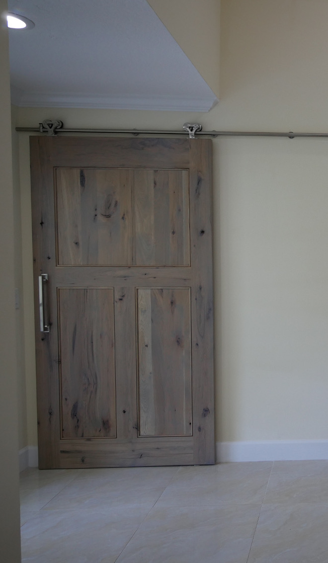 Driftwood Barn door. This summer the couple decided to carry the rustic hickory further into the house with the addition of a barn door concealing the laundry room. This 140LB. solid hickory door is a wonderful sight upon entering this gorgeous home. Barn Door: Crystal Cabinets, Rustic Hickory, Driftwood Stain with Brown Brushing. Barn Door Hardware: Hickory Hardware, Studio Collection #DriftwoodBarndoor Waterview Kitchens