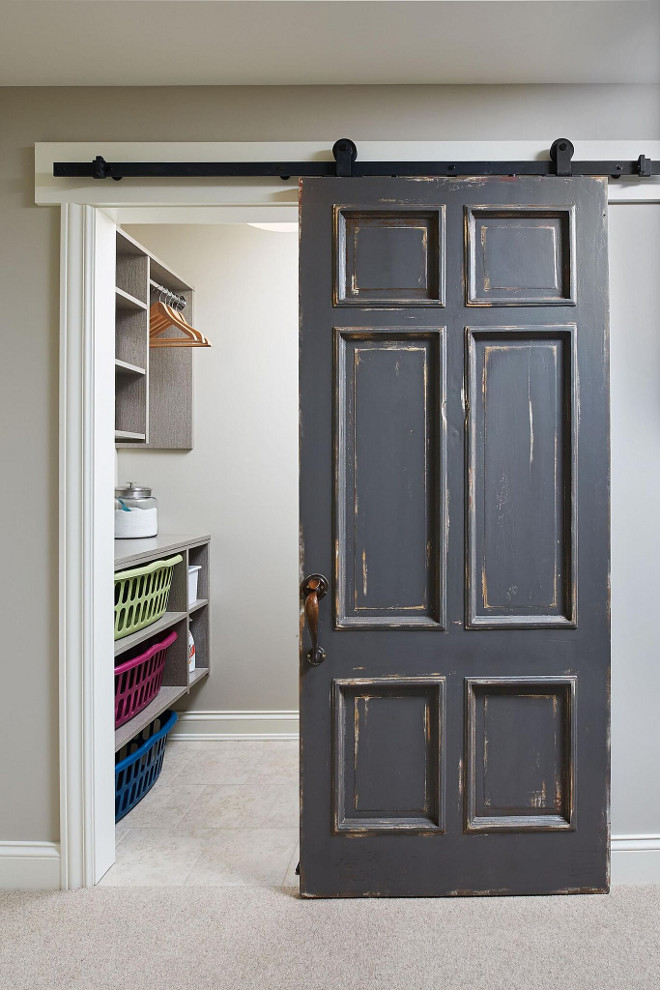 Distressed Barn Door. An old door, painted in Benjamin Moore HC-166 Kendall Charcoal is hung on barn door hardware as a sliding barn door to conceal the laundry room. Mike Schaap Builders