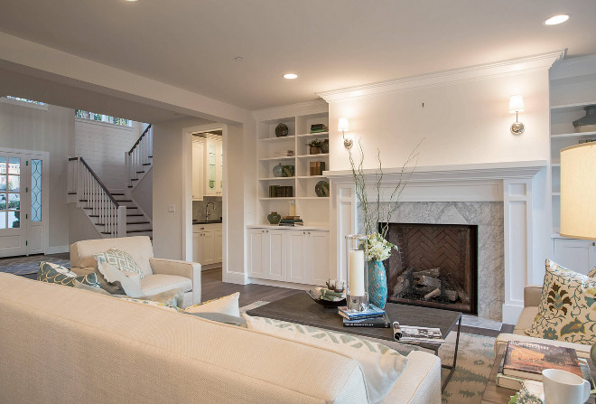 The foyer opens to the formal living room with marble surround fireplace flanked by bookshelves. Paint Color Benjamin Moore OC-130 Cloud White. #formallivingroom #marblesurroundfireplace #bookshelves Calista Interiors