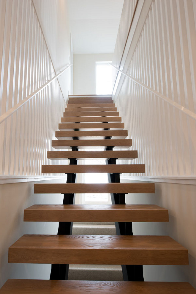 This modern farmhouse stairway features metal steel stringers, white oak threads and painted steel on the sides. #farmhouse #stairway #modernfarmhouse #whiteoakthreads #staircasethreads #steel #stringers Refined Custom Homes