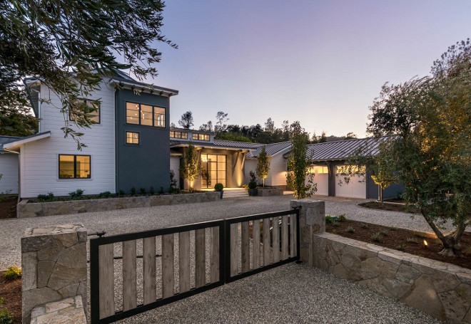 Modern Farmhouse. Modern Farmhouse Exterior. Gated Modern Farmhouse with gravel driveway, custom barn wood gate, black steel windows and metal roof #graveldriveway #barnwood #exposedbeams, blacksteelwindows #metalroof #modernfarmhouse Holder Design Associates