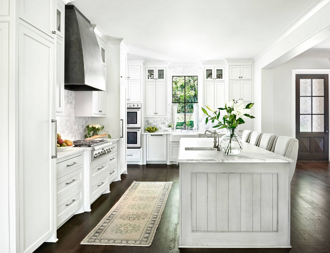 White kitchen with dark hardwood floors, zinc hood, Bianco carrara backsplash tile and black steel window. White kitchen with dark hardwood floors, zinc hood and black steel window ideas. Countertops are honed Calacatta Gold marble with an cove ogee edge. White kitchen with dark hardwood floors, zinc hood and black steel window #Whitekitchen #darkhardwoodfloors #zinchood #blacksteelwindow Forte Building Group LLC