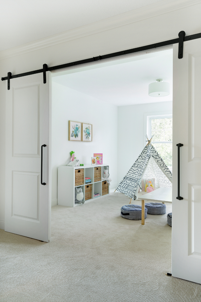 Flex room playroom with barn doors. The landing area opens to a flex room, currently used as a playroom. Bria Hammel Interiors